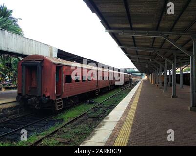 Piattaforma vuota di una stazione ferroviaria in Sri Lanka. Vecchie auto arrugginite. Sembra un luogo abbandonato, ma non lo è Foto Stock