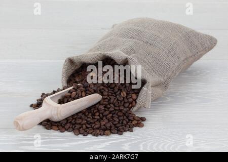 Cucchiaio per chicchi di caffè e sacchetto sulla superficie in legno Foto Stock