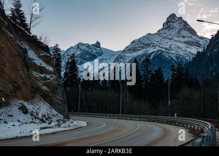 Girando la strada di montagna per la stazione sciistica di sera Foto Stock