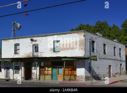 Scarpe rosse appendere da filo di testa vicino a un funky run down vecchio edificio con segno per affitto di appartamenti, nella città di confine messicano di Nogales, AZ, Stati Uniti Foto Stock