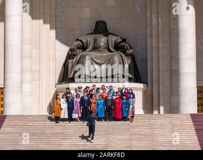 Persone in abito tradizionale e formale che posano da Genghis Khan statua per la foto, Sükhbaatar Square, Ulaanbaatar, Mongolia Foto Stock