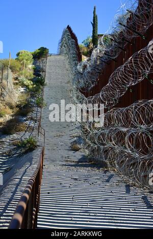 Vista del confine internazionale USA/Messico con filo di rasoio in salita con il Messico dall'altro lato del recinto da Nogales, AZ, USA Foto Stock