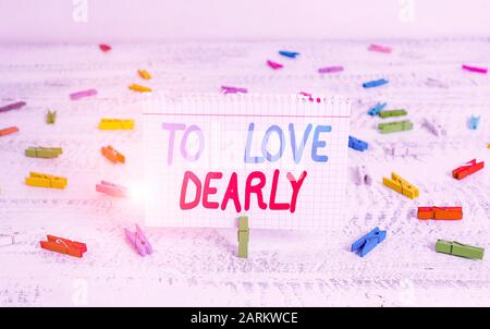 La grafia la scrittura di testo per amare teneramente. Foto concettuale amare qualcuno molto più in modo umile e smarrendosi clothespin verde legno bianco indietro Foto Stock