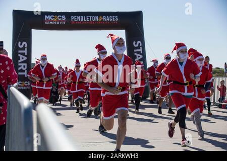 I membri del servizio e le loro famiglie voleranno dalla linea di partenza durante la Santa Run presso l'Assault Craft Unit 5 Compound sul campo base del corpo della Marina Pendleton, California, 15 dicembre 2019. La Santa Run fa parte della Hard Corps Race Series tenuta dai Marine Corps Community Services. MCC è un insieme completo di programmi che sostengono e migliorano la disponibilità operativa, le capacità di lotta contro la guerra e la qualità della vita di Marines, delle loro famiglie, dei pensionati e dei civili. (STATI UNITI Foto del corpo marino di Lance Cpl. Andrew Cortez) Foto Stock