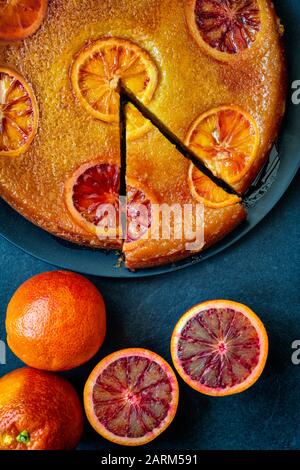 Torta di arance di sangue fatta in casa capovolta con sciroppo d'arancia di sangue su uno sfondo di ardesia Foto Stock