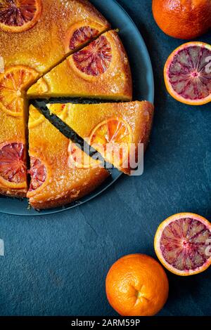 Torta di arance di sangue fatta in casa capovolta con sciroppo d'arancia di sangue su uno sfondo di ardesia Foto Stock