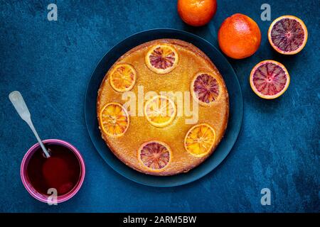 Torta di arance di sangue fatta in casa capovolta con sciroppo d'arancia di sangue su uno sfondo di ardesia Foto Stock