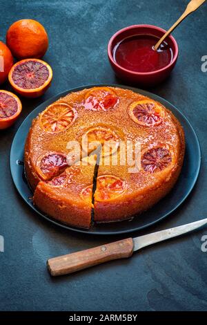 Torta di arance di sangue fatta in casa capovolta con sciroppo d'arancia di sangue su uno sfondo di ardesia Foto Stock