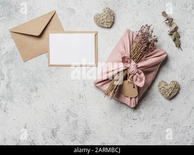 Zero rifiuti San Valentino concetto e mock up. Eco-friendly confezione di tessuto regalo in stile Furoshiki, carta artigianale busta, regalo vuoto o carta di auguri, copia spazio Foto Stock