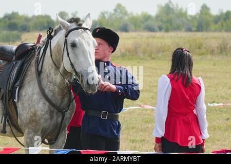 Samara, Russia - 07 Ottobre 2019: giovani e cosacco cosacco ragazza in costumi nazionali in piedi accanto al cavallo. La ragazza dice addio al Cossac Foto Stock