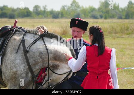 Samara, Russia - 07 Ottobre 2019: giovani e cosacco cosacco ragazza in costumi nazionali in piedi accanto al cavallo. La ragazza dice addio al Cossac Foto Stock