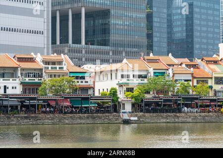 Singapore. Gennaio 2020. Il contrasto tra le case dei negozi lungo il fiume Singapore e i moderni grattacieli sullo sfondo Foto Stock