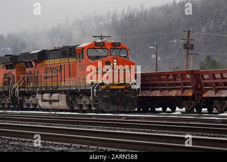 Una locomotiva BNSF nera, gialla e arancione, che gira al minimo sulle piste nella città di Troy, Montana. Burlington Northern e Santa Fe Railway sono stati formati in Foto Stock