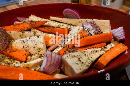Carote cipolle pastinache e aglio pronti per essere arrostiti al forno con erbe per il pranzo invernale arrosto Fotografia presa da Simon Dack Foto Stock