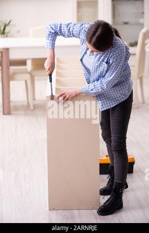 Il giovane bella donna di assemblaggio di mobili a casa Foto Stock