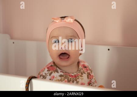 ritratto di un bambino carino nel vestito rosa nel suo letto Foto Stock