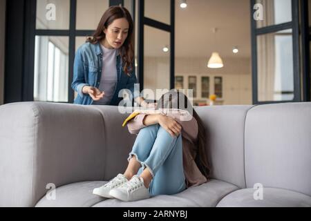 Piangendo la figlia che nasconde il suo volto e la mamma che sta accanto a lei. Foto Stock