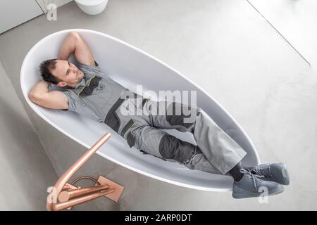 Caucasici Uomini In Una Vasca Da Bagno Autoportante Godendo Di Bagno Ristrutturato Di Recente. Appena Finito Duro Lavoro. Concetto Di Miglioramento Domestico. Golden Floor Montato Fre Foto Stock