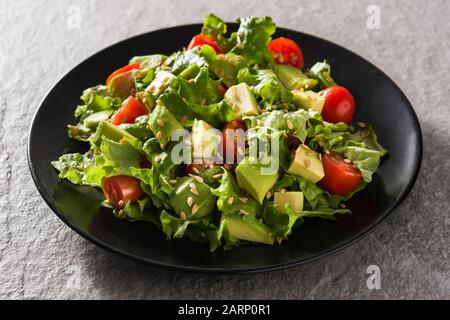Insalata con avocado, lattuga, pomodoro e semi di lino su sfondo grigio Foto Stock