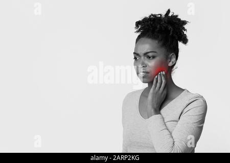 Giovane donna nera che tocca una guancia, che sente dolore Foto Stock