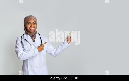 Giovane terapeuta femminile nera in hijab che punta allo spazio della copia Foto Stock