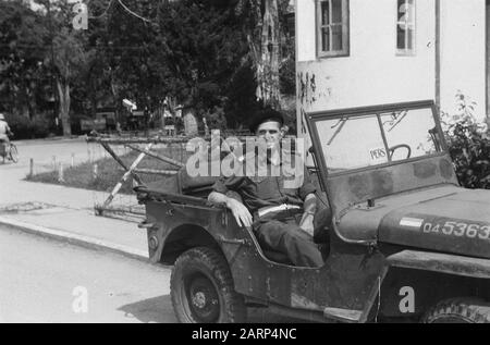 Sergente Maggiore polizia militare KNIL pone in jeep. Sul parabrezza, il segno premere. Dietro di lui sono blocchi mobili che punta a una caserma come posizione Annotazione: Jeep numero di registrazione: D4-5363 Data: 1947/01/01 luogo: Indonesia, Dutch East Indies Foto Stock