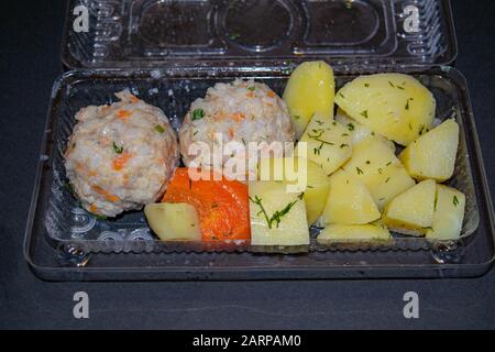 polpette di carne con patate bollite e carote bollite in un contenitore di plastica su sfondo scuro. Primo piano Foto Stock