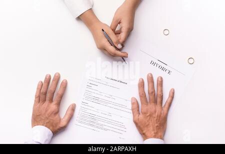 Mani di moglie, marito firma decreto di divorzio Foto Stock
