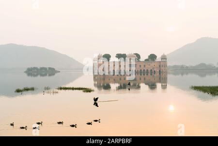 Palazzo reale vuoto circondato da lago e colline di Aravalli come sfondo all'alba a Jaipur, Rajasthan, India. Foto Stock