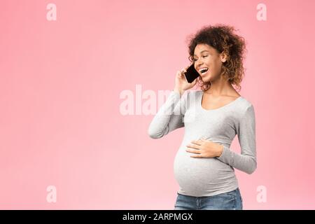 Donna incinta felice nero consultare con il medico al telefono Foto Stock