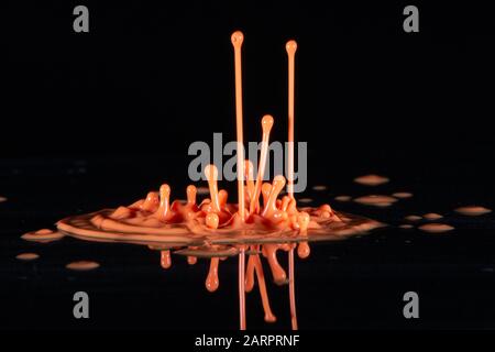 Arancione schizzi di inchiostro su sfondo nero Foto Stock