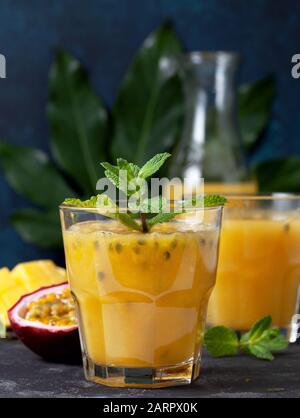 frullato mango frutto della passione in un bicchiere, fresco mango e frutto della passione su sfondo scuro Foto Stock