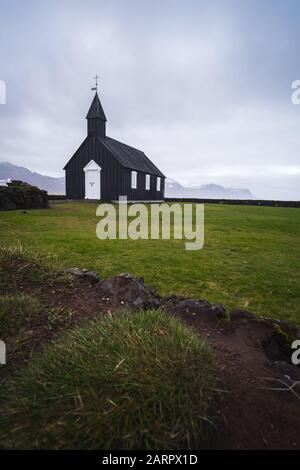 Búðakirkja, la chiesa nera costiera dell'Islanda, situata sulla costa meridionale della penisola di Snæfellsnes dell'Islanda. Splendida porta bianca e spettacolare Foto Stock