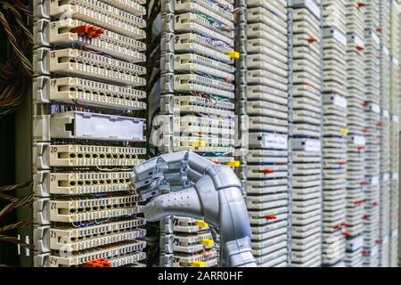 Il braccio meccanico del robot si trova accanto al quadro della telefonia ip. Il robot lavora nella sala server del data center Foto Stock