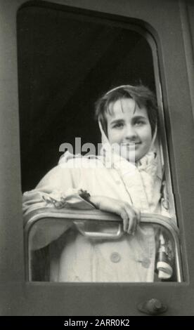 Una ragazza che si inclina fuori dalla finestra del treno, Italia 1960 Foto Stock
