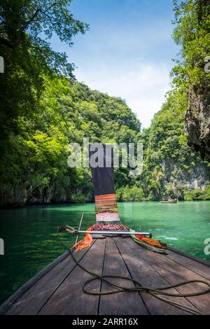 Una barca a coda lunga entra in una laguna appartata nella Baia di Phang Nga, Thailandia Foto Stock