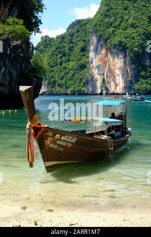 Imbarcazione Thai a coda lunga ancorata nella baia di Phang Nga, Thailandia. Formazioni rocciose carsiche in lontananza Foto Stock