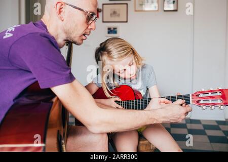 padre che insegna a sua figlia come suonare la chitarra - insegnamento, apprendimento, hobby concetto Foto Stock