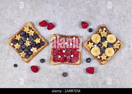 Cibo sano con fette di pane tostato farro condito con frutta come lampone rosso, mirtillo, banana e cereali di quinoa soffiato Foto Stock