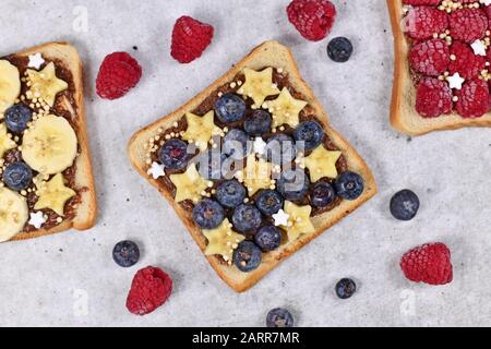 Cibo sano con fetta di pane tostato farro sormontato da frutti di mirtillo, fette di banana a forma di stelle e quinoa soffiato grani Foto Stock