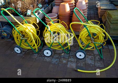 Tre mercati giardino avvolgitubo con giallo attorcigliare il tubo flessibile resistente su bobine portatile ed avente ugelli di spruzzo distribuzione conveniente in un garden center Foto Stock