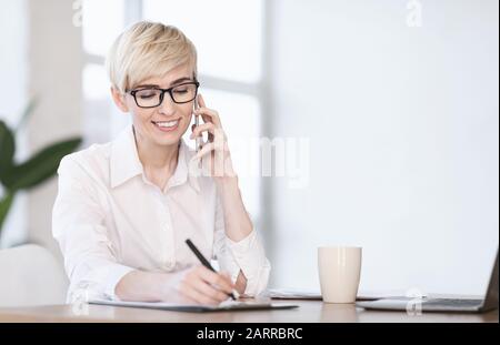Donna Imprenditore Che Parla Sul Telefono Prendere Appunti Seduti Sul Posto Di Lavoro Foto Stock