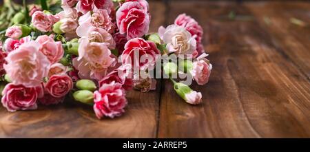 Bouquet di garofani rosa, bouquet di regali su sfondo ligneo. Concezione di cartoline con l'aggiunta di testo. Spazio di copia .Banner. Foto Stock