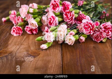 Bouquet di garofani rosa, bouquet di regali su sfondo ligneo. Concezione di cartoline con l'aggiunta di testo. Spazio di copia . Foto Stock