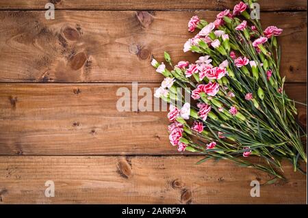 Bouquet di garofani rosa, bouquet di regali su sfondo ligneo. Concezione di cartoline con l'aggiunta di testo. Spazio di copia . Foto Stock