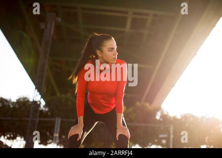 Attraente femmina giovane runner prendendo pausa dopo il jogging all'aperto Foto Stock