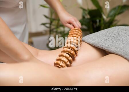 Closeup del massaggio anti-cellulite della maderoterapia con massaggiatore a rulli in legno Foto Stock