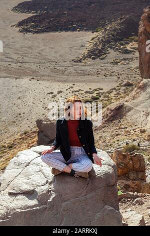 giovane donna meditando su roccia affiorare alto sopra valle Foto Stock