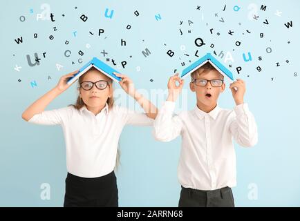 Piccoli allievi carini con libri e molte lettere su sfondo a colori Foto Stock