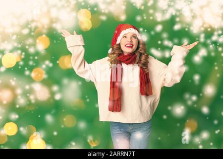 Giovane donna felice in abiti invernali su sfondo colorato con neve Foto Stock